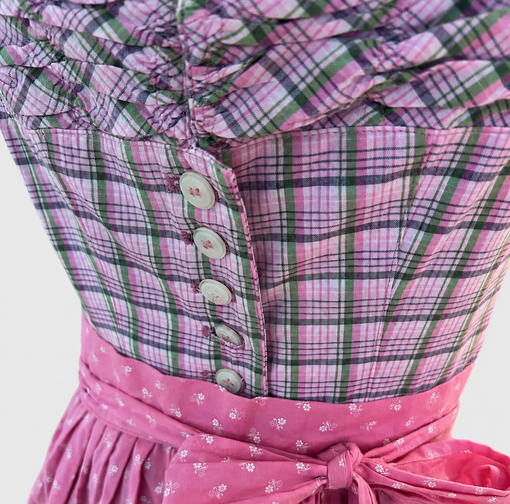 Close-up of Berwin & Wolff Dirndl with pink checked bodice, white buttons and bright pink apron bow