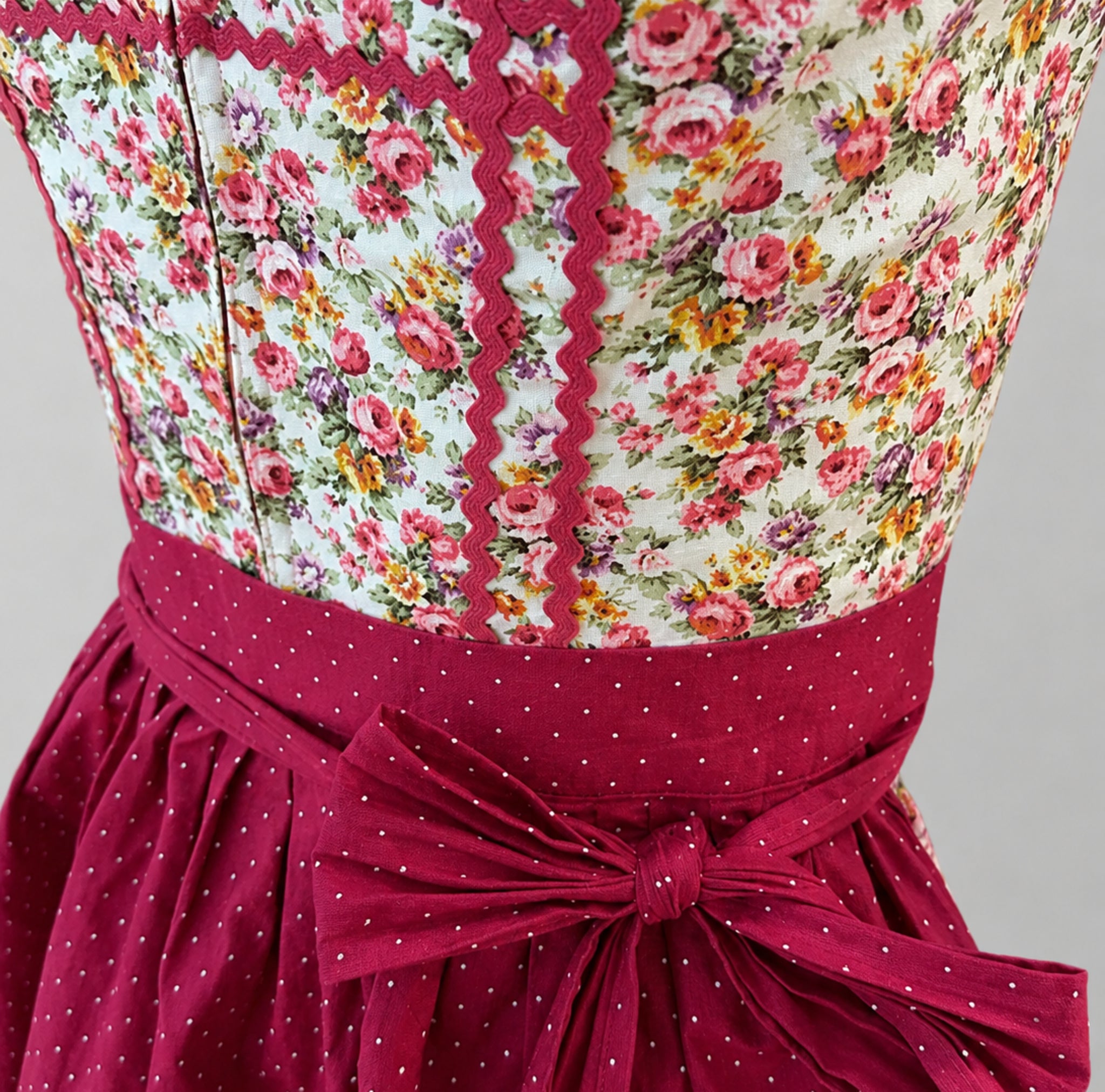 Close-up of Berwin & Wolff Dirndl with floral bodice, red trim and dotted apron bow