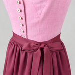 Detail of pink Heimatgwand Dirndl bodice with square neckline, decorative buttons and burgundy apron
