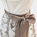 Detail of Krüger gold Dirndl with cream bodice, taupe waist bow and ivory floral lace apron