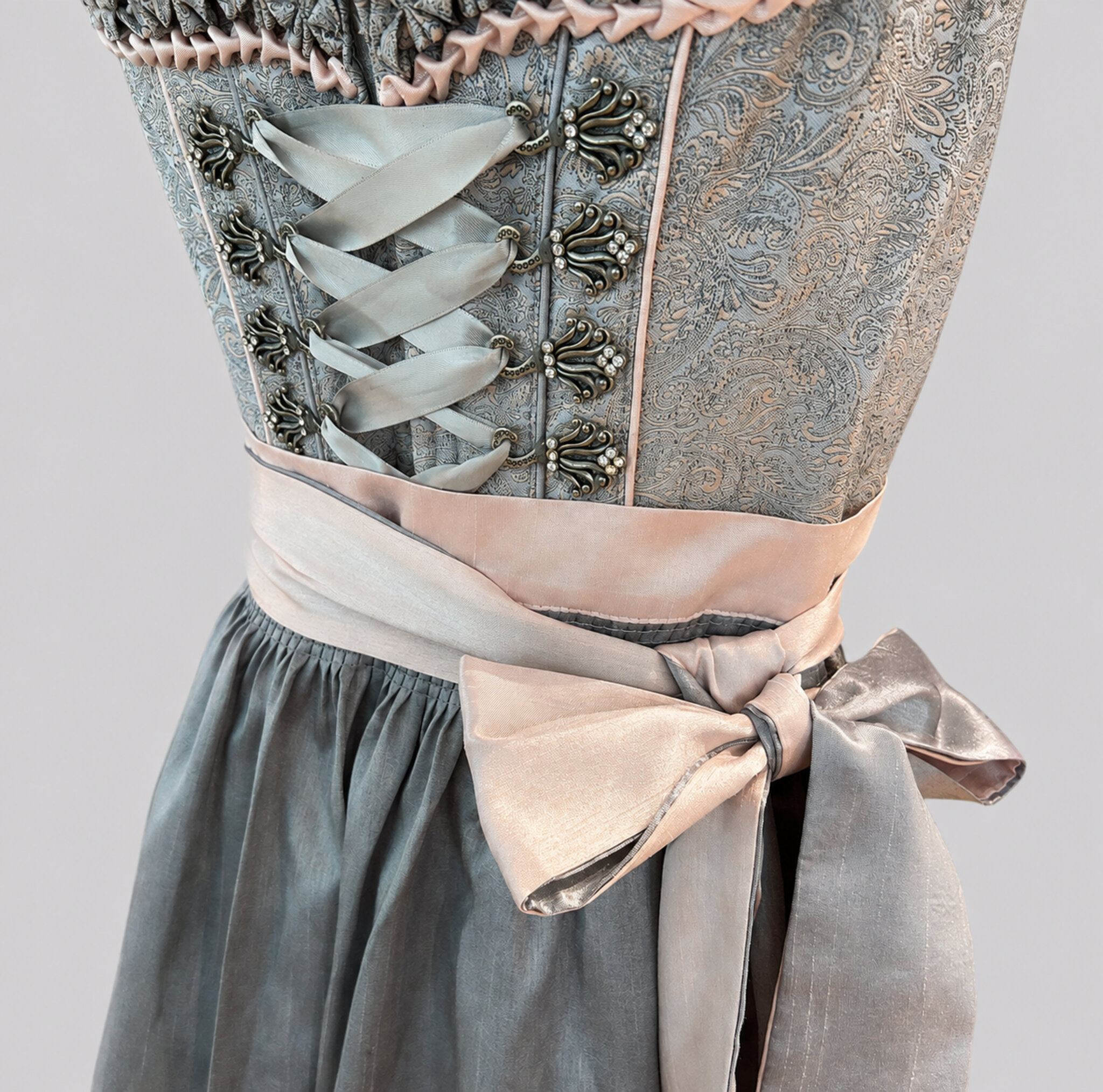 Detail of grey Krüger Dirndl bodice with ornamental hooks, ribbon lacing and soft pink apron bow