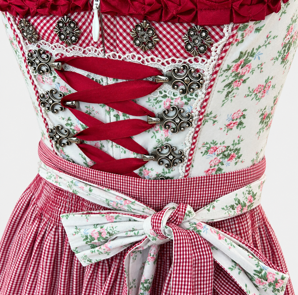 Detail of Krüger Madl floral bodice with bordeaux ribbon lacing, ornate silver-toned hooks and floral apron bow