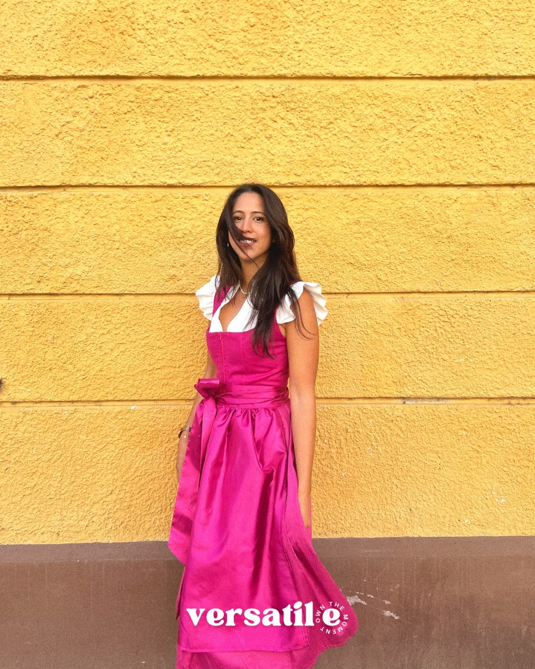 Rent Ma.Le.Ma artisanal fuchsia silk dirndl in Munich—handcrafted square-neck bodice, flowing skirt, tied bow apron; ideal for Oktoberfest.