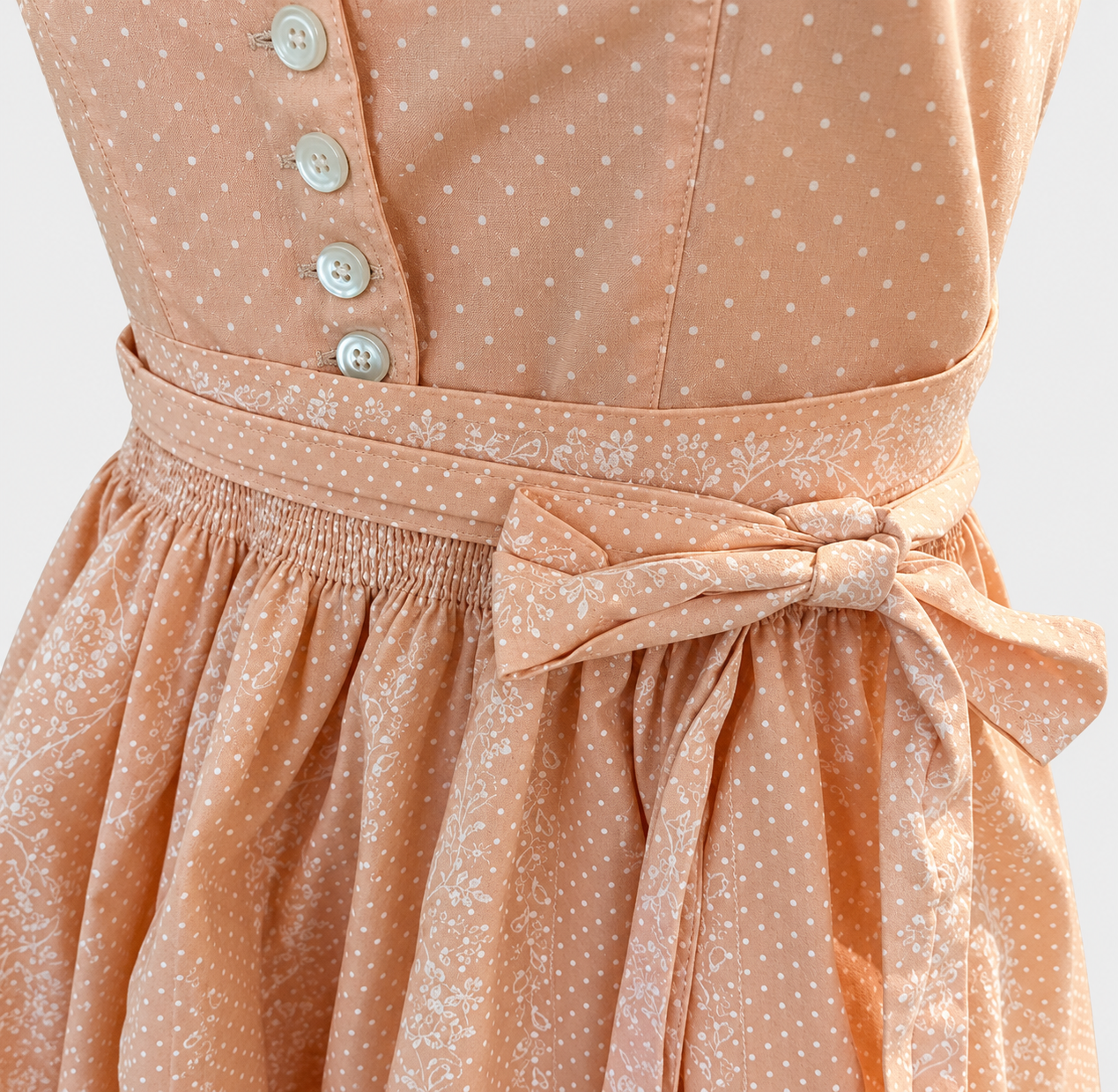 Detail of Turi Landhaus apricot Dirndl with white buttons, dotted bodice and floral apron bow