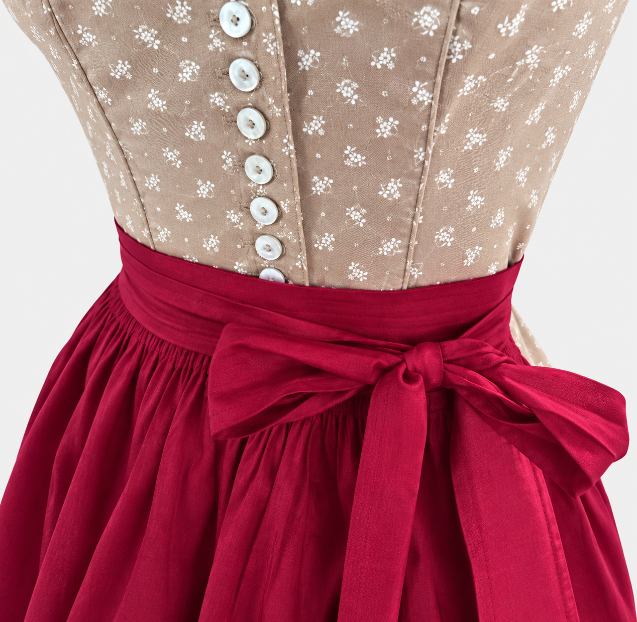 Detail of Wenger beige bodice with small white flowers, light buttons and berry red apron bow