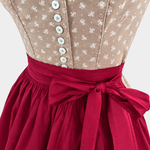 Detail of Wenger beige bodice with small white flowers, light buttons and berry red apron bow